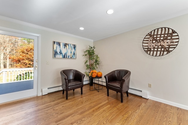 sitting room with baseboard heating, light hardwood / wood-style flooring, and ornamental molding