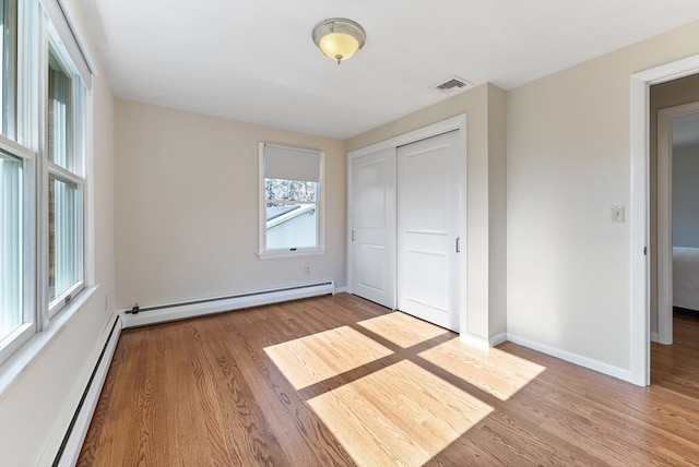 unfurnished bedroom with a closet, light hardwood / wood-style floors, and a baseboard radiator