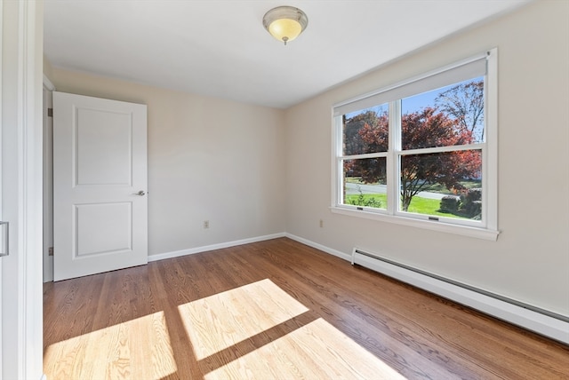 spare room featuring a baseboard radiator and light hardwood / wood-style floors