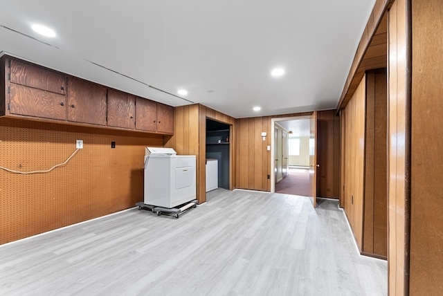 clothes washing area with wood walls, light hardwood / wood-style floors, and washer / clothes dryer