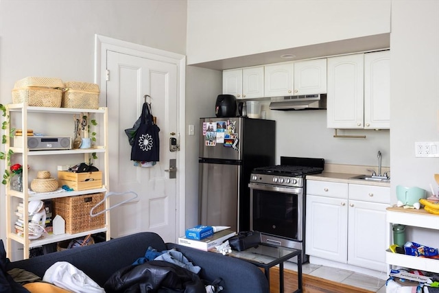 120 Charles St, Boston, MA 02114 - kitchen with stainless steel appliances, under cabinet range hood, a sink, white cabinets, and light countertops