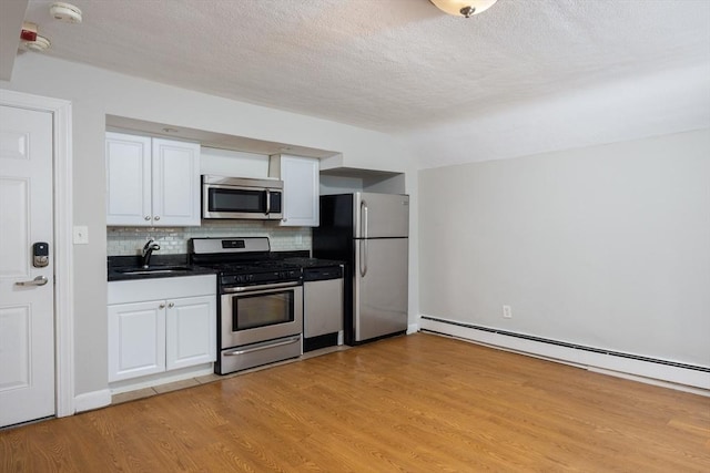 120 Charles St, Boston, MA 02114 - kitchen with appliances with stainless steel finishes, a sink, dark countertops, white cabinetry, and light wood-type flooring
