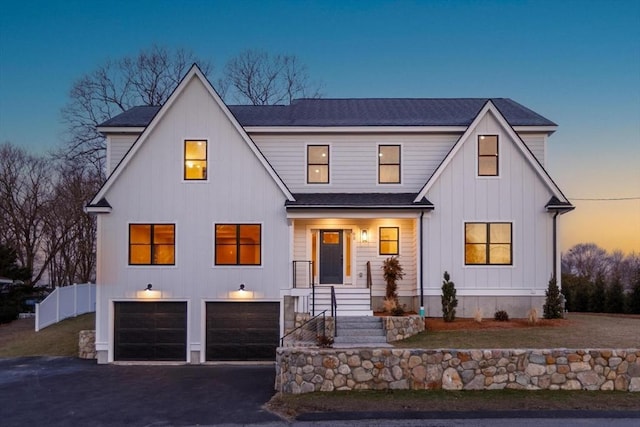 modern farmhouse style home featuring aphalt driveway, fence, board and batten siding, roof with shingles, and a garage