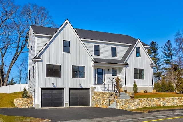 modern farmhouse with fence, driveway, a shingled roof, a garage, and board and batten siding