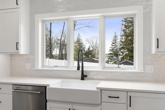 kitchen with white cabinetry, a sink, light countertops, stainless steel dishwasher, and tasteful backsplash