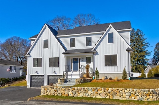 modern farmhouse style home with a garage, a front yard, board and batten siding, and driveway