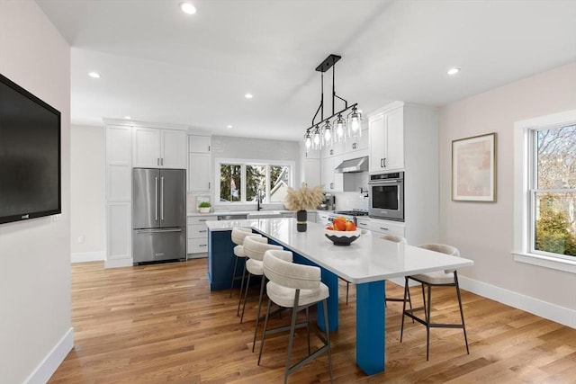 kitchen with stainless steel appliances, plenty of natural light, extractor fan, and a breakfast bar