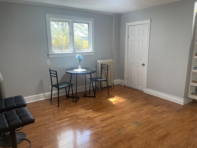 sitting room with radiator heating unit, baseboards, and wood finished floors