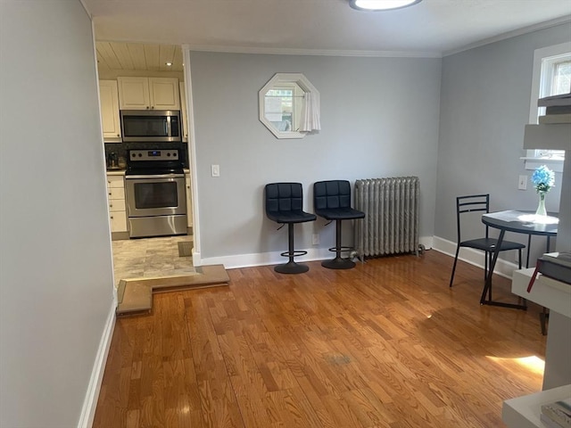 kitchen with stainless steel appliances, baseboards, radiator, and light wood-type flooring