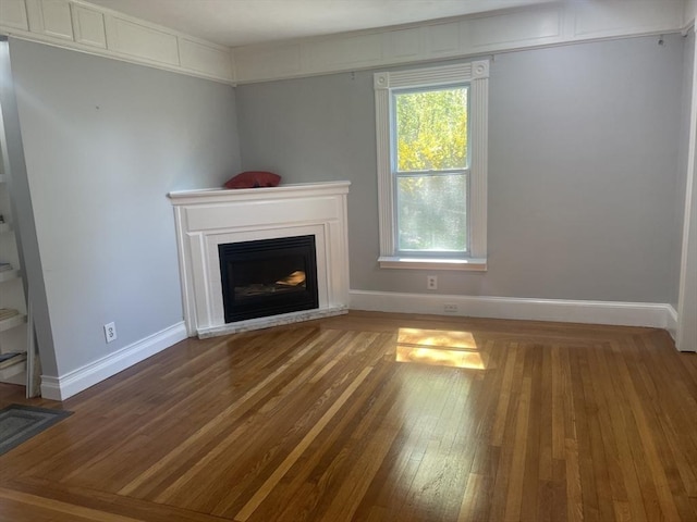 unfurnished living room with baseboards, wood finished floors, and a fireplace