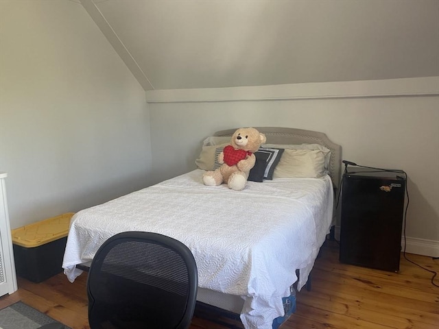 bedroom with baseboards, vaulted ceiling, and wood finished floors