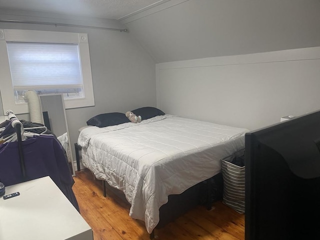 bedroom with light wood-type flooring and lofted ceiling