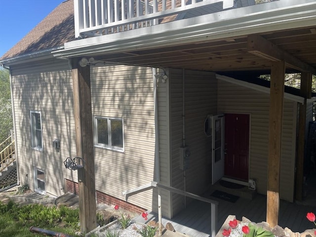 view of side of property featuring a shingled roof and a balcony