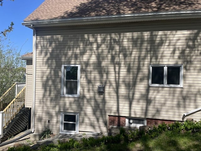 view of side of home featuring a shingled roof and stairs