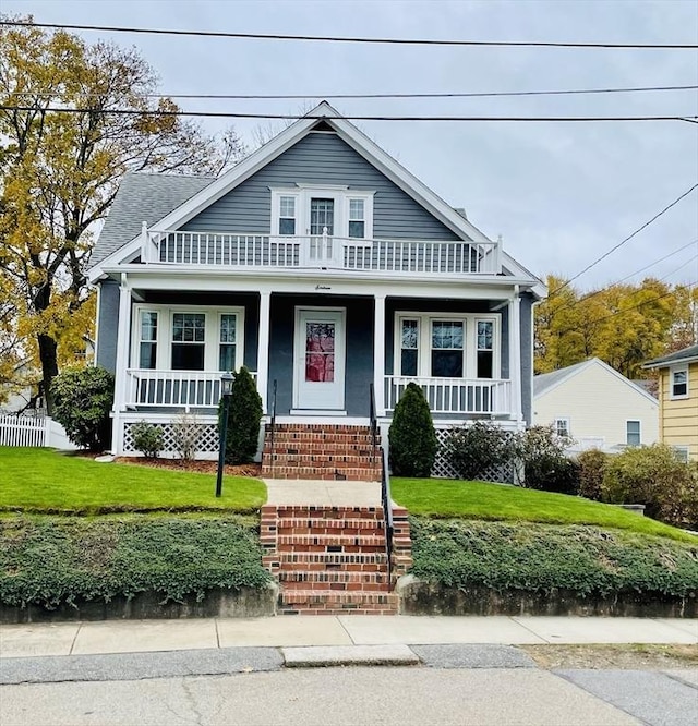 view of front of house featuring a balcony, covered porch, and a front lawn