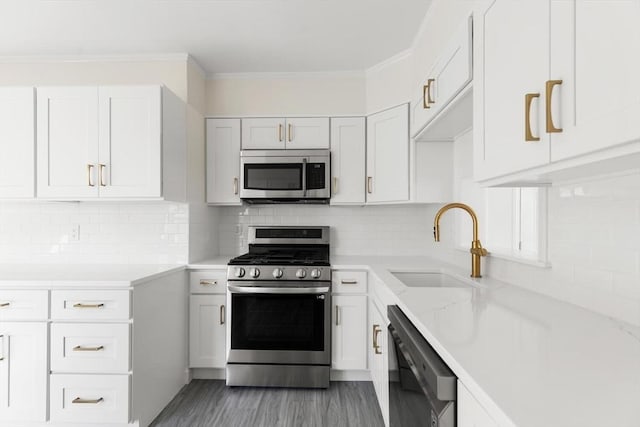 kitchen featuring sink, appliances with stainless steel finishes, white cabinetry, tasteful backsplash, and ornamental molding