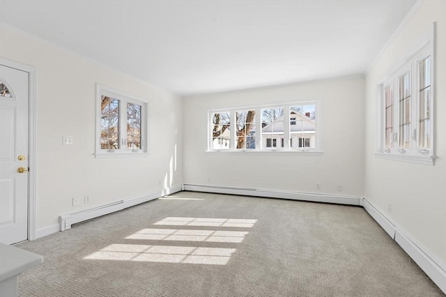 carpeted empty room with baseboard heating, ornamental molding, and plenty of natural light