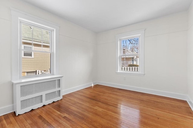 spare room featuring wood-type flooring and radiator