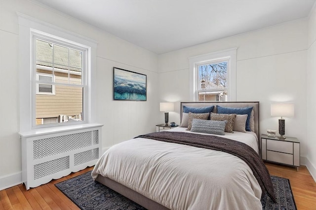 bedroom with radiator and hardwood / wood-style flooring