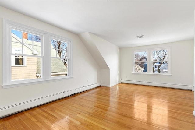 additional living space featuring a baseboard radiator, plenty of natural light, and light hardwood / wood-style floors