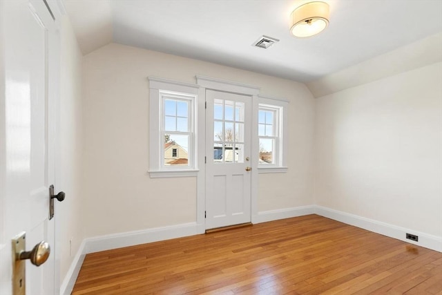 spare room with vaulted ceiling and light hardwood / wood-style floors