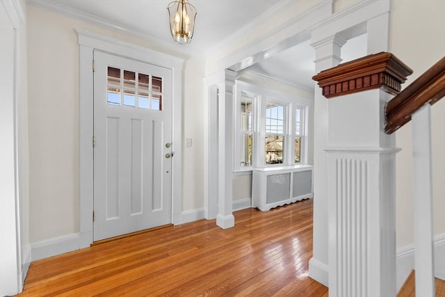 entryway featuring crown molding, radiator heating unit, light hardwood / wood-style floors, and decorative columns