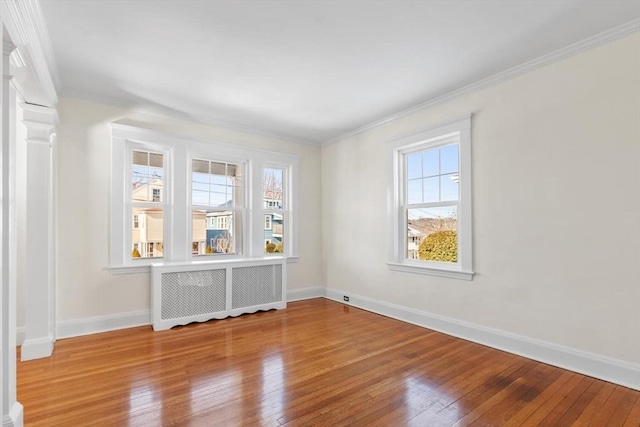 empty room featuring crown molding, wood-type flooring, and radiator