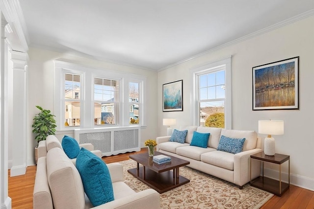 living room with crown molding, ornate columns, and light wood-type flooring