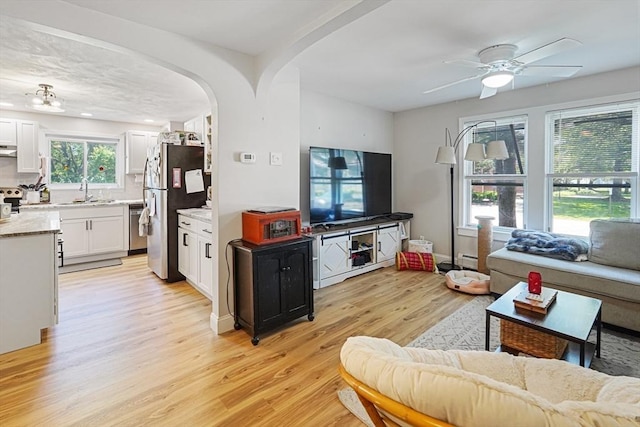 22 Tampa St, Worcester, MA 01604 - living room with light wood-style flooring, ceiling fan, arched walkways, and a baseboard radiator