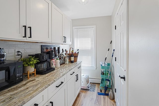 22 Tampa St, Worcester, MA 01604 - kitchen with black microwave, tasteful backsplash, light wood-style flooring, light stone counters, and white cabinetry