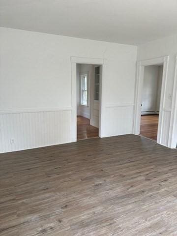 678 School St, Webster, MA 01570 - empty room with wood finished floors, a wainscoted wall, and a baseboard radiator