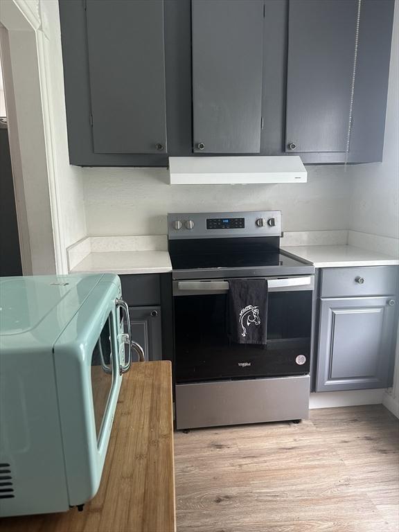 678 School St, Webster, MA 01570 - kitchen with stainless steel range with electric stovetop, white microwave, extractor fan, gray cabinets, and light countertops
