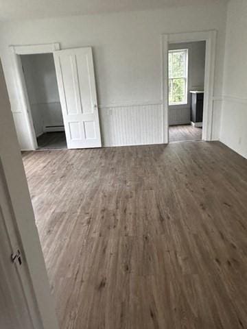 678 School St, Webster, MA 01570 - empty room with wood finished floors, baseboard heating, and wainscoting