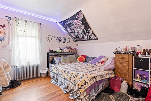 bedroom with lofted ceiling, hardwood / wood-style floors, and radiator