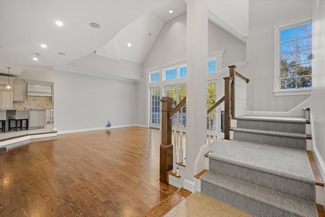 staircase featuring wood-type flooring and high vaulted ceiling