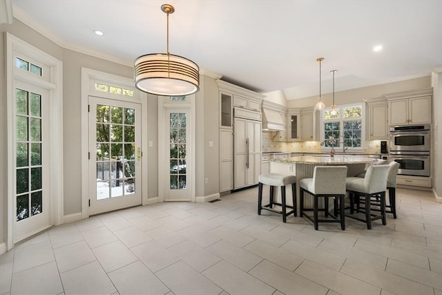 kitchen with double oven, hanging light fixtures, a center island, light stone counters, and paneled fridge