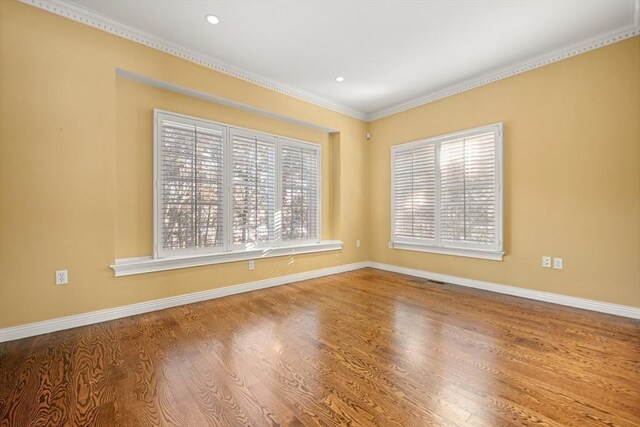 empty room with ornamental molding, a healthy amount of sunlight, and hardwood / wood-style floors