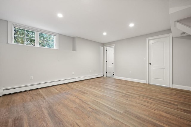 basement with a baseboard radiator and light hardwood / wood-style floors