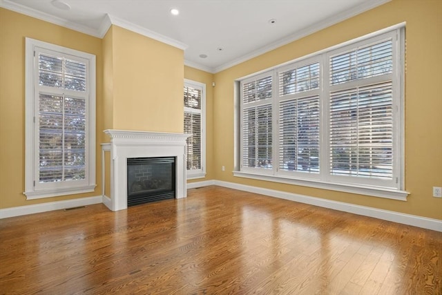 unfurnished living room featuring hardwood / wood-style flooring, ornamental molding, and plenty of natural light