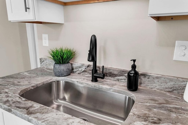 room details with light stone countertops, white cabinetry, and sink