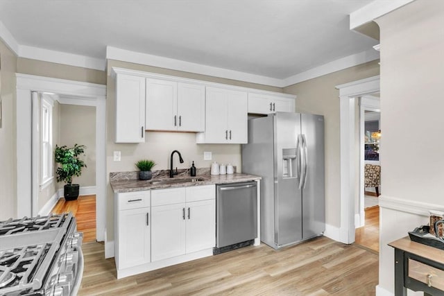 kitchen with white cabinets, light stone counters, sink, and appliances with stainless steel finishes