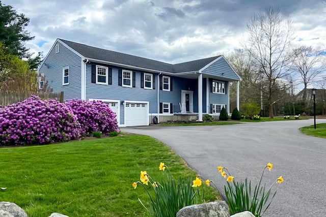 bi-level home featuring driveway, an attached garage, and a front yard