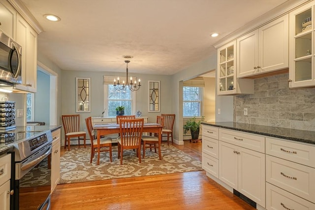 dining room featuring light wood finished floors, baseboards, an inviting chandelier, and recessed lighting