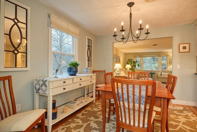 dining area featuring baseboards, wood finished floors, a wealth of natural light, and an inviting chandelier