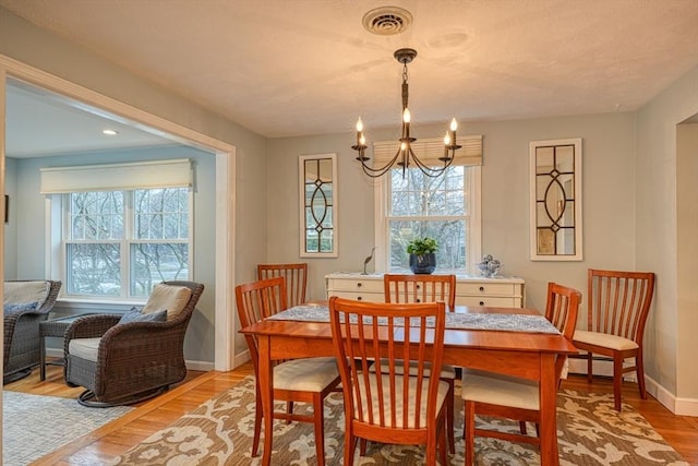 dining room with light wood-style flooring, visible vents, baseboards, and a wealth of natural light