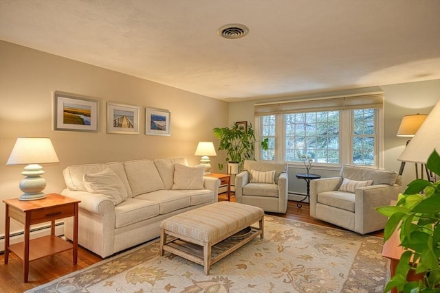 living room featuring visible vents, baseboard heating, and light wood-style flooring