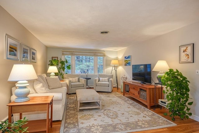 living room with baseboards, visible vents, and wood finished floors