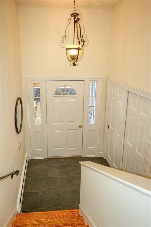 foyer with a baseboard radiator and a towering ceiling