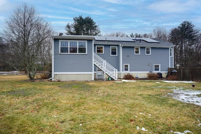 view of front of property featuring entry steps, solar panels, stairway, and a front yard