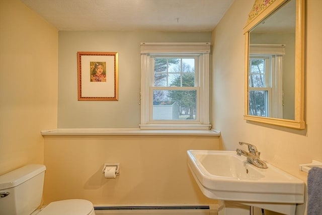 bathroom with toilet, plenty of natural light, a baseboard radiator, and a sink